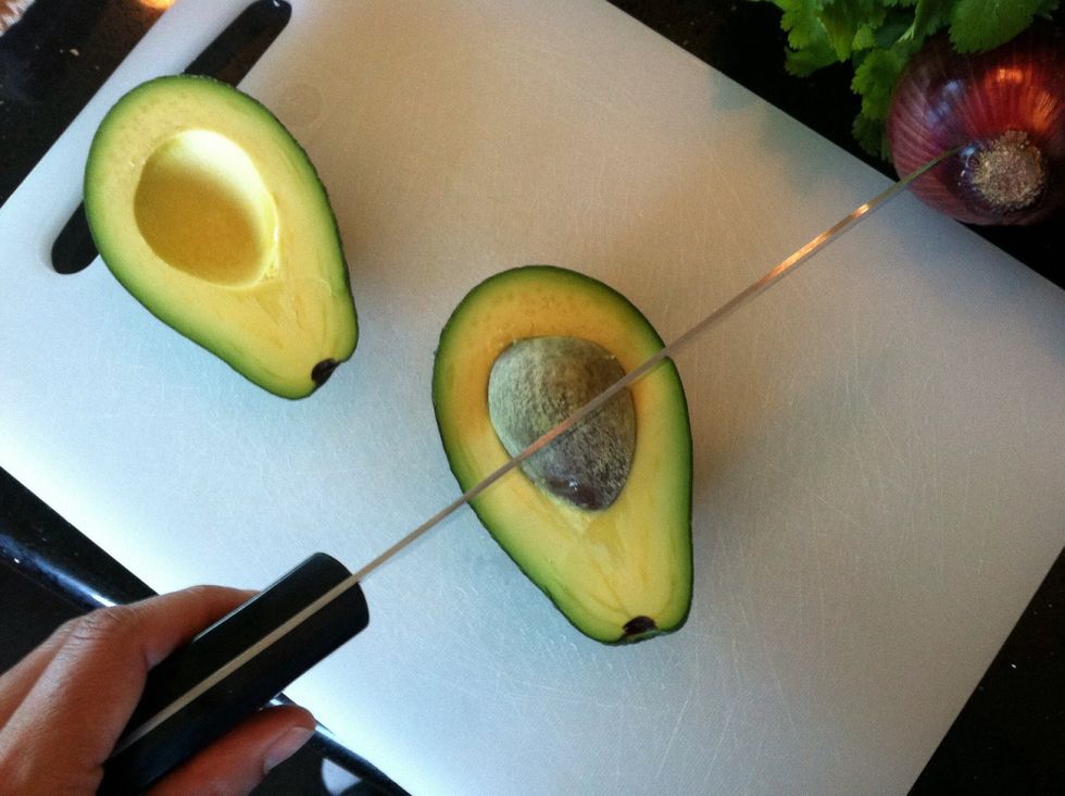 Slice the avocado. Then hold it in the palm of your hand & lightly hit the pit with the knife blade (be careful). Hit the pit hard enough for the blade to get stuck in it.