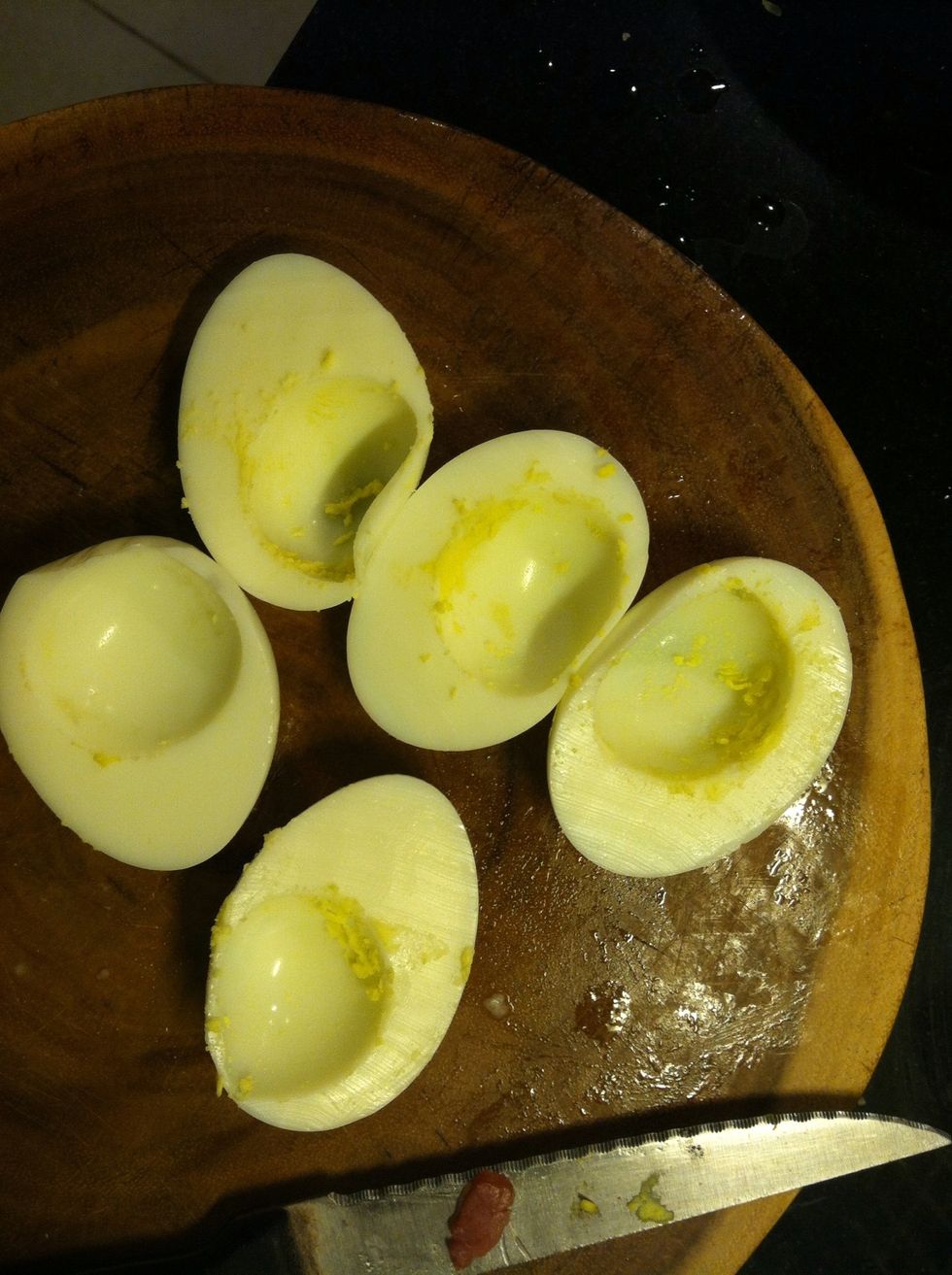 Slice the eggs lengthwise like this and then scrape the cooked egg yolk. Put all the egg yolk in a bowl.