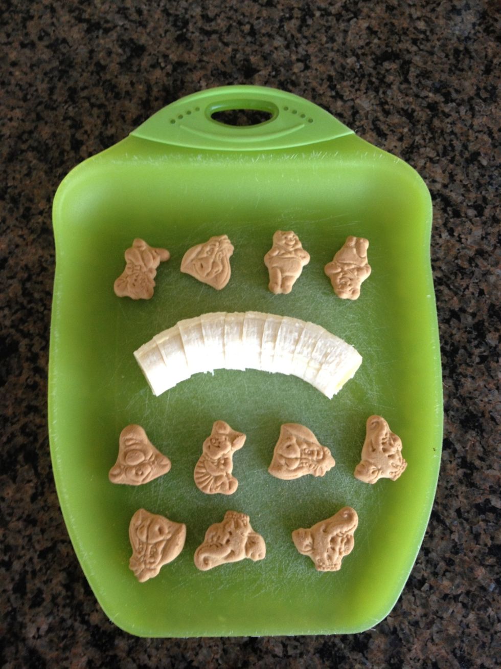 Slice the now frowning banana and place a number of animal cookies on your preparation surface. (I'm going with a bulk purchased delicacy of Winnie the Pooh characters for maximum flavor)