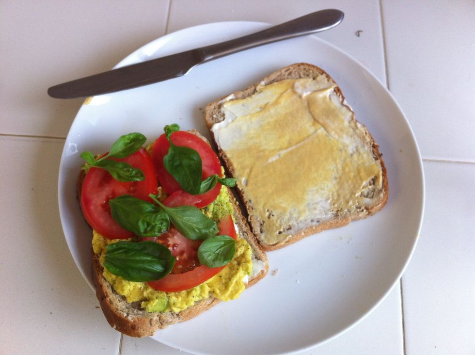 Slice tomato to desired thickness, add to avocado, then top with just a few leaves of fresh basil.