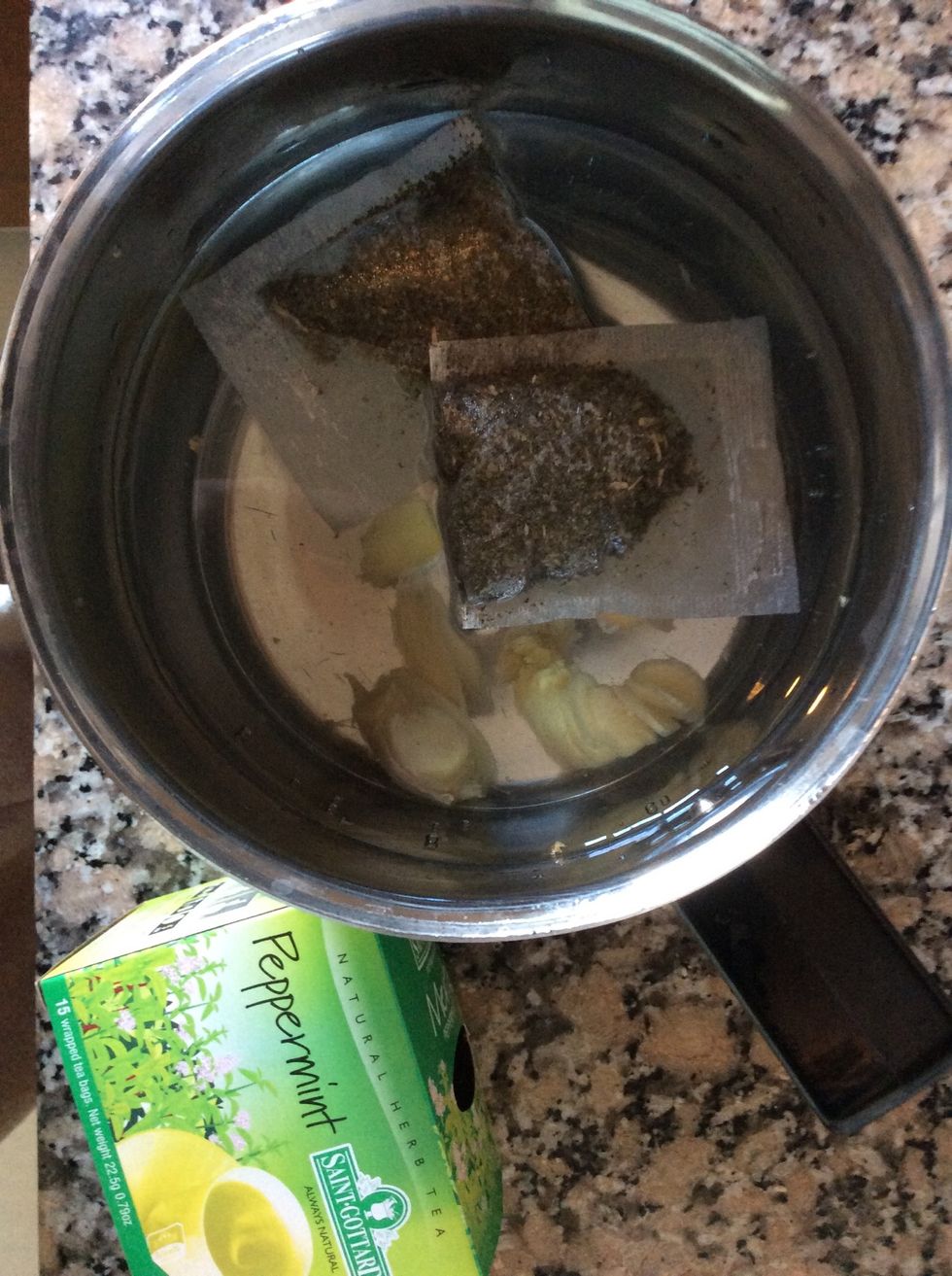 Slice up peeled ginger as finely as possible, add to water in a saucepan with peppermint teabags. Bring to the boil. Remove teabags and leave on the boil 3 minutes. Remove any frothy bits.