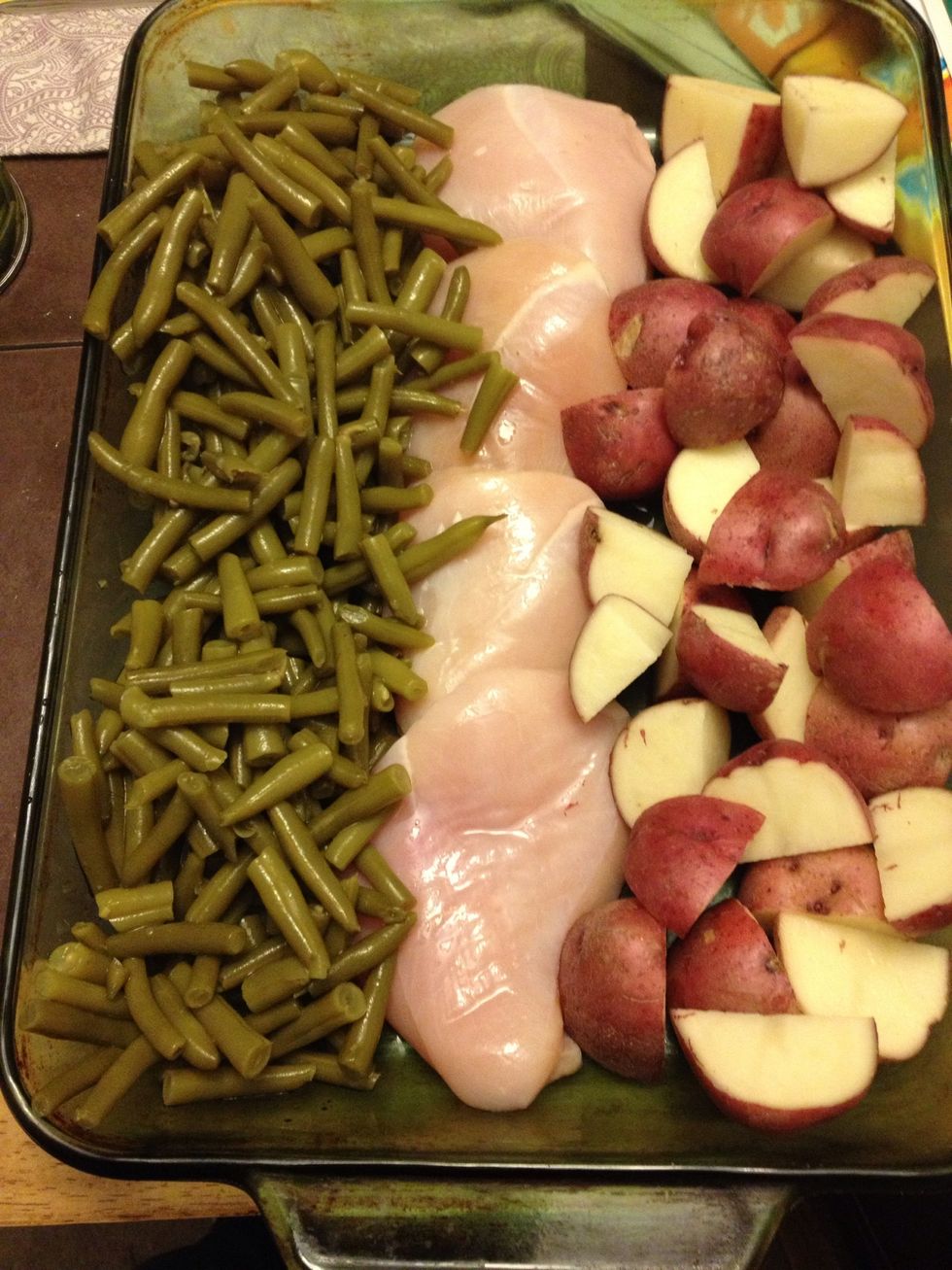 Slice you potatoes into four halves Drain both cans of green beans Clean the fat off the chicken Pour the melted butter onto the beans and potatoes and sprinkle the Italian dressing over the food.