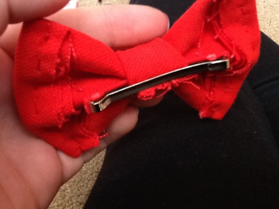 Slide a clip through the fabric that is holding the bow together