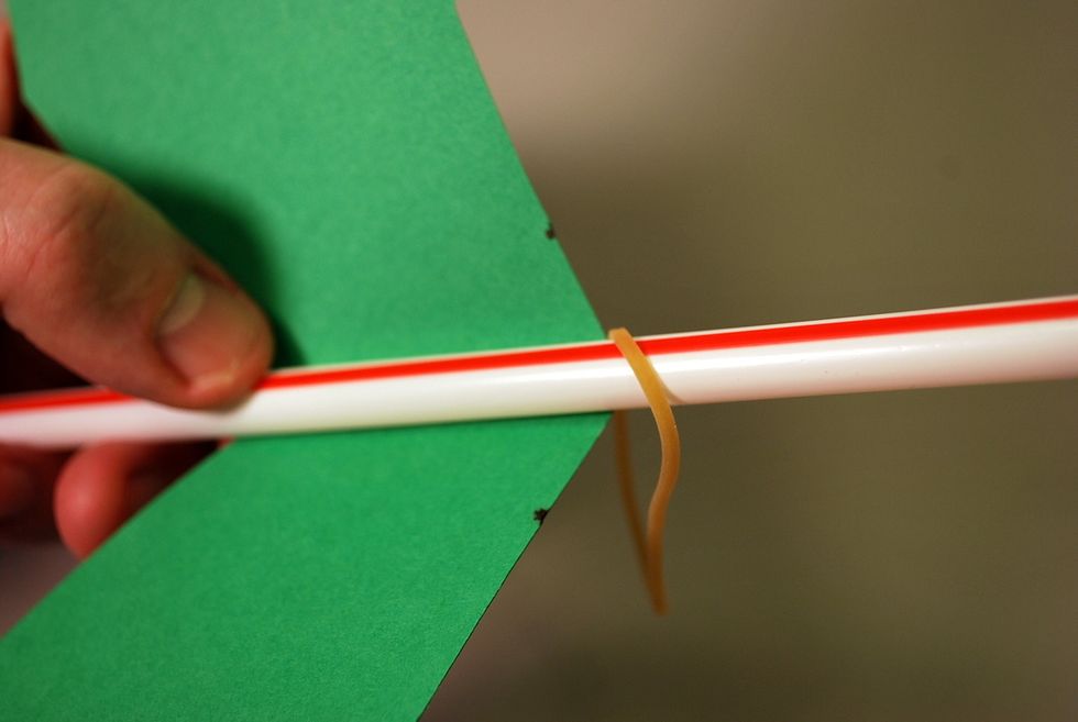 Slide one end of the rubber band on the straw down to the wing.