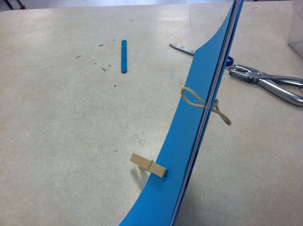 Slide rubber band through one hole. Don't pull rubber and all the way through.