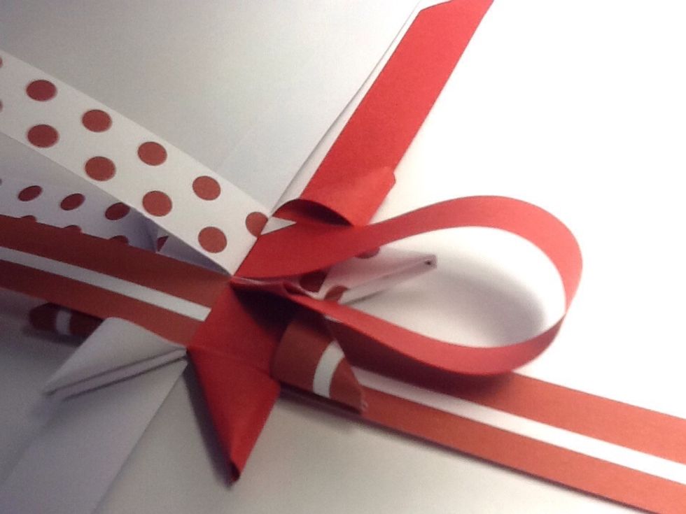 Slide the (in this case ) red strip under the bent - back spotted strip