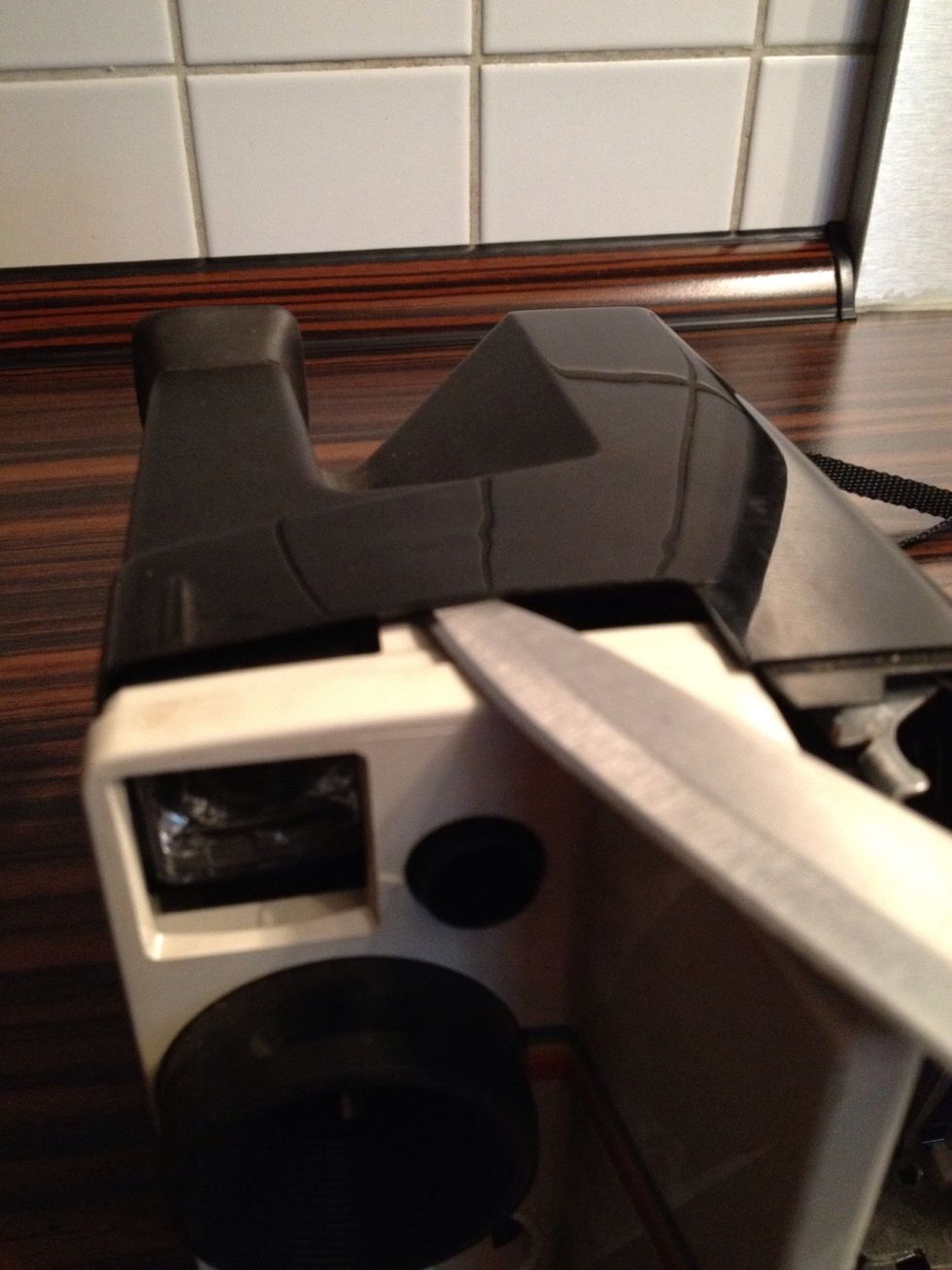 Slide the knive gently into the camera on both sides and push the case to the outside while pulling the white part to the front