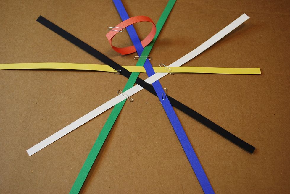 Slide the orange loop so that the blue strip that is under the green strip is through the loop. Keep it so the orange loop is touching the point of the star as shown above.