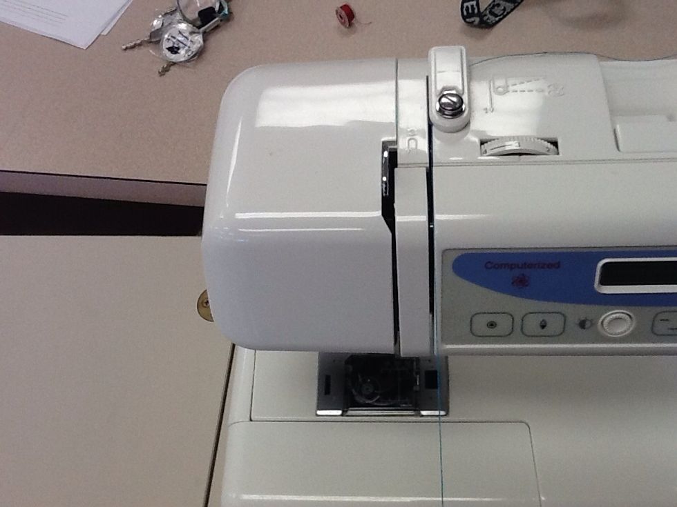 Slide the thread down into the grove to the right of the upper thread guide and then swing it up the left side of the column.