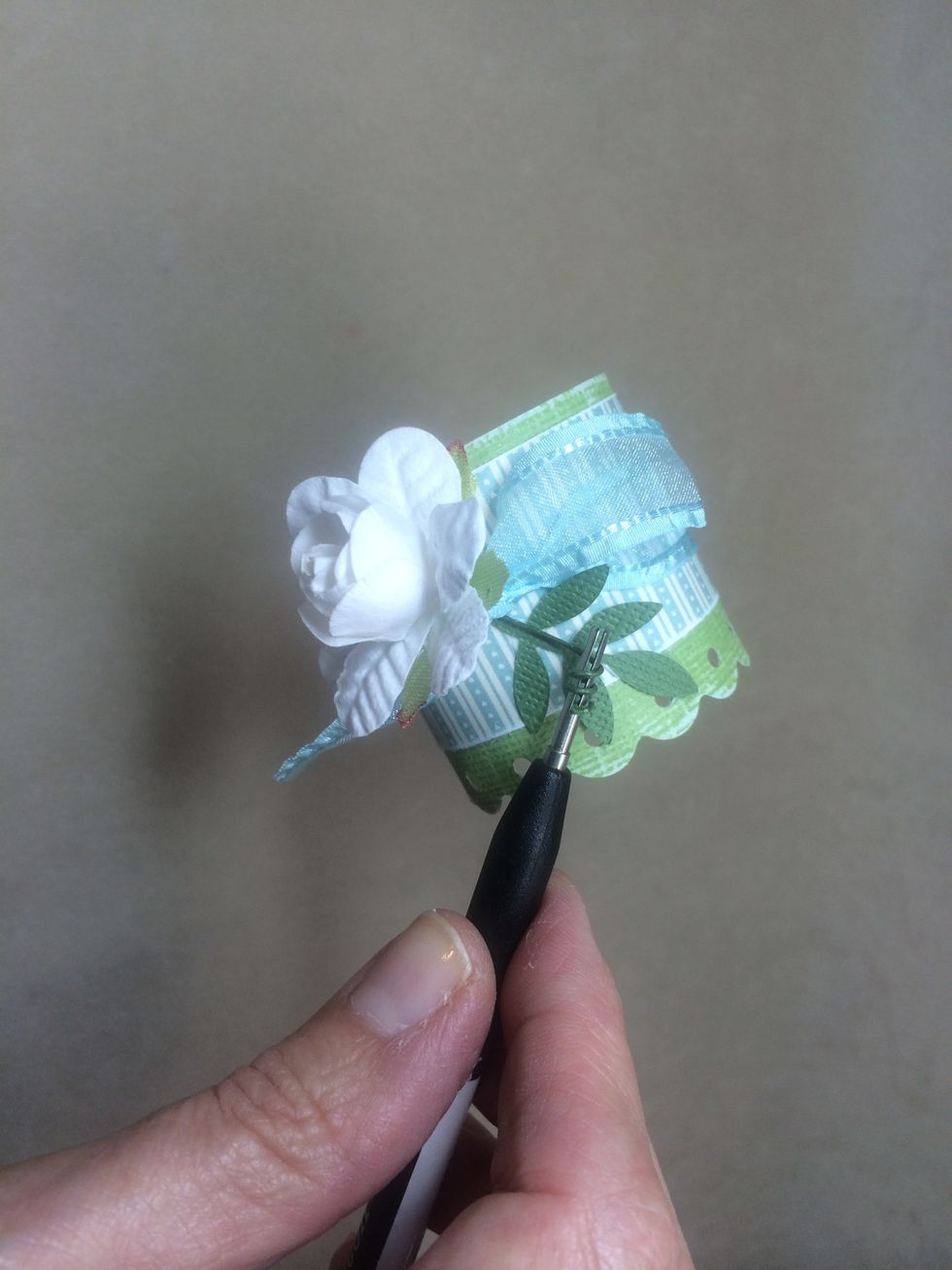 Slide the wire stem of a craft flower under the knot. Use hot glue to secure flower to ring, then curl the wire stem. I used a quilling tool.