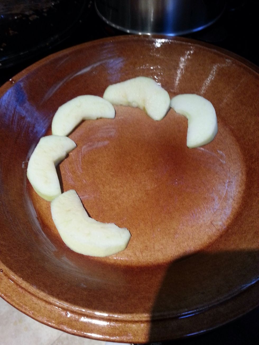 Slightly grease a wide casserole bowl with butter, the dish shouldn't be too deep. Peel and slice the apple, they should be roughly half a centimetre thick. Then start layering the apple in the dish.