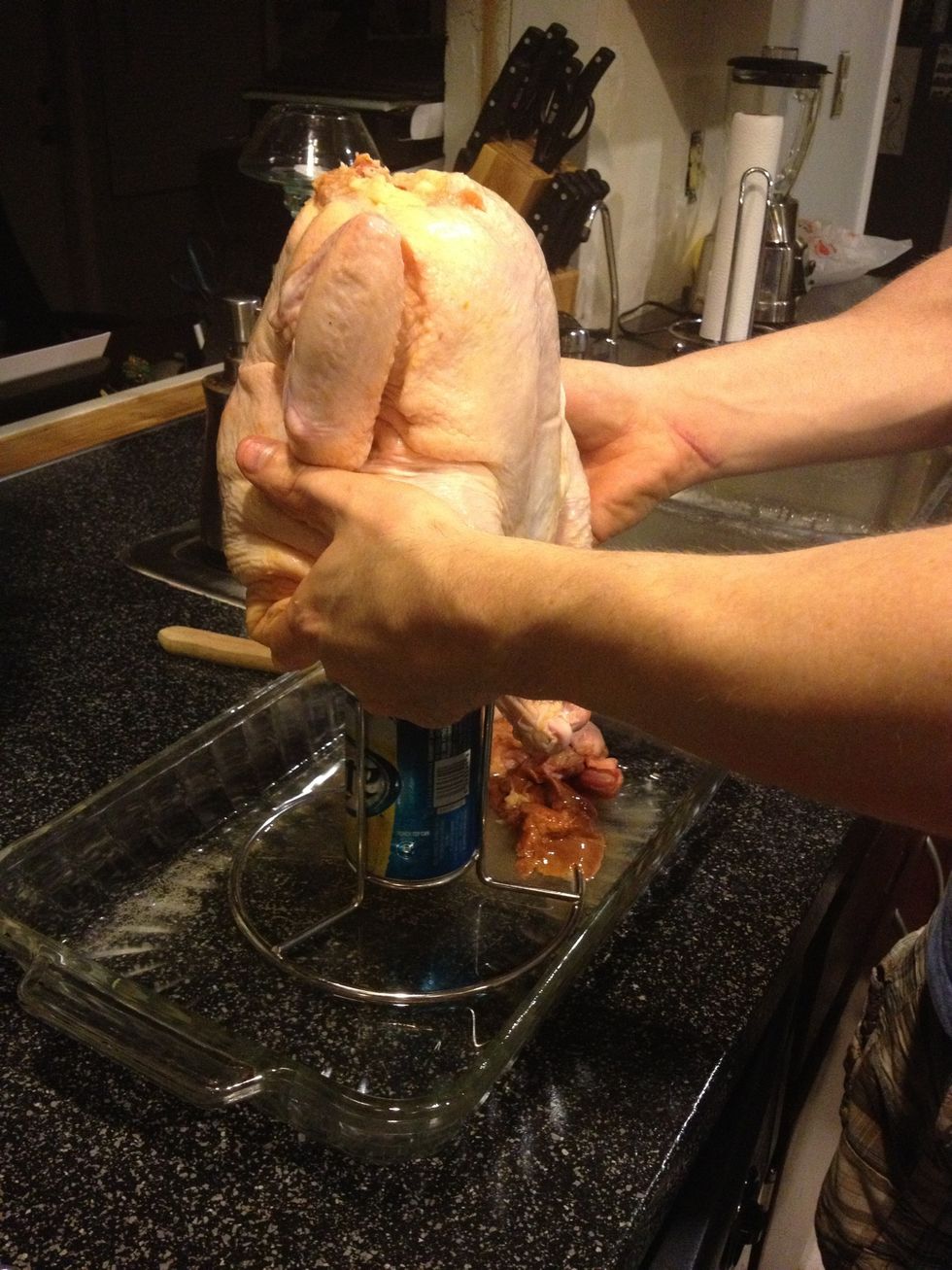 Slowly place the chicken over the beer.