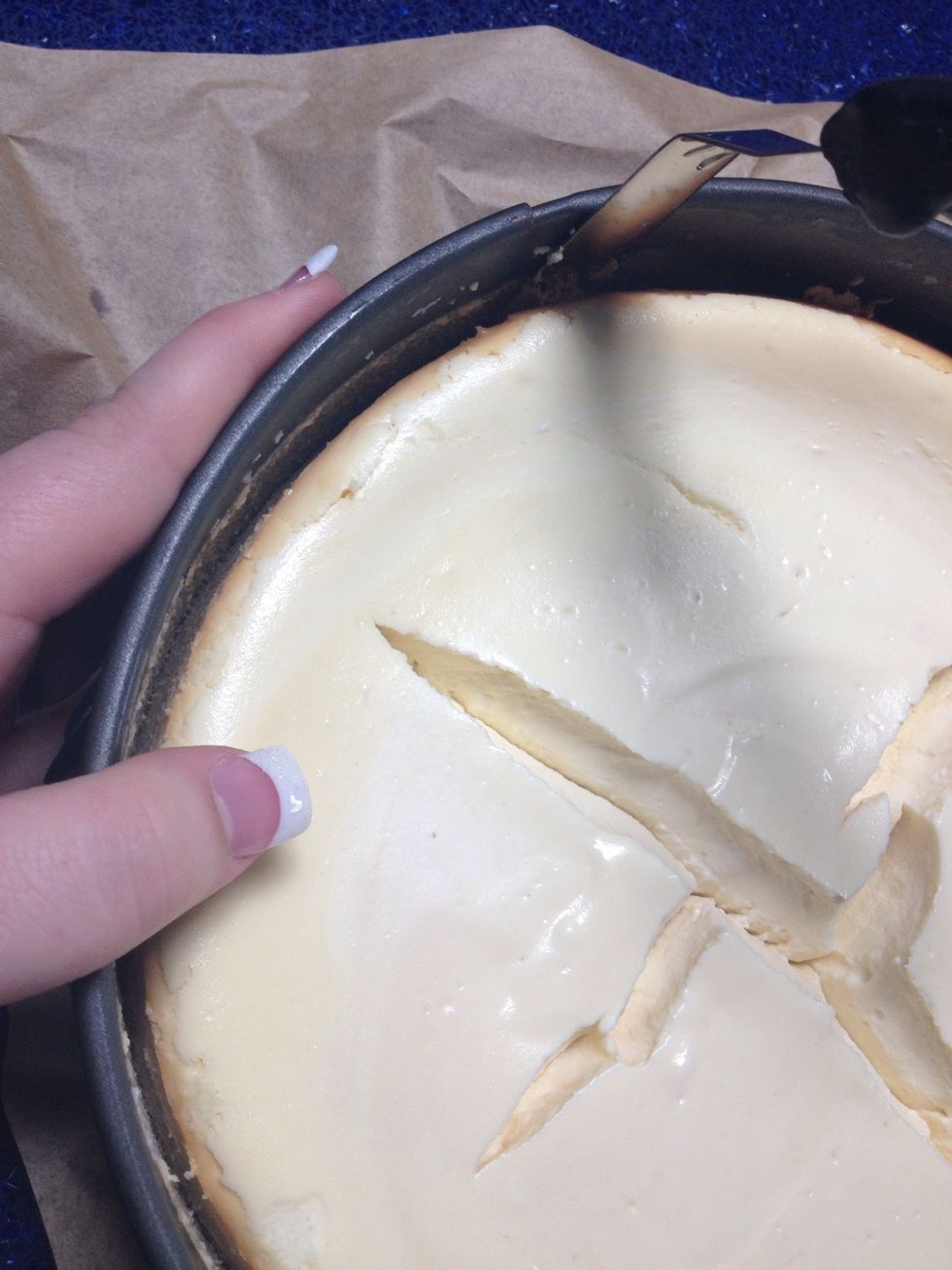 Slowly slide the icing spreader around the sides of the pan, turning the pan with your other hand.