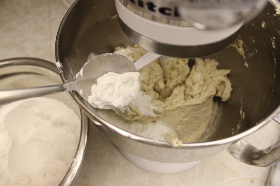 Slowly spoon in the flour mixture into the stand mixer while it's running on low to gradually blend in the dry ingredients into the wet ingredients.