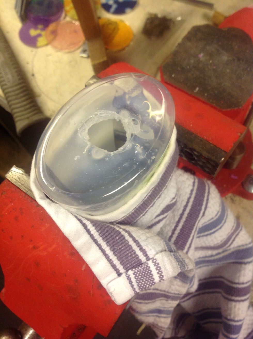 Slowly, with steady pressure, drill a hole in the top of the soap bottle.