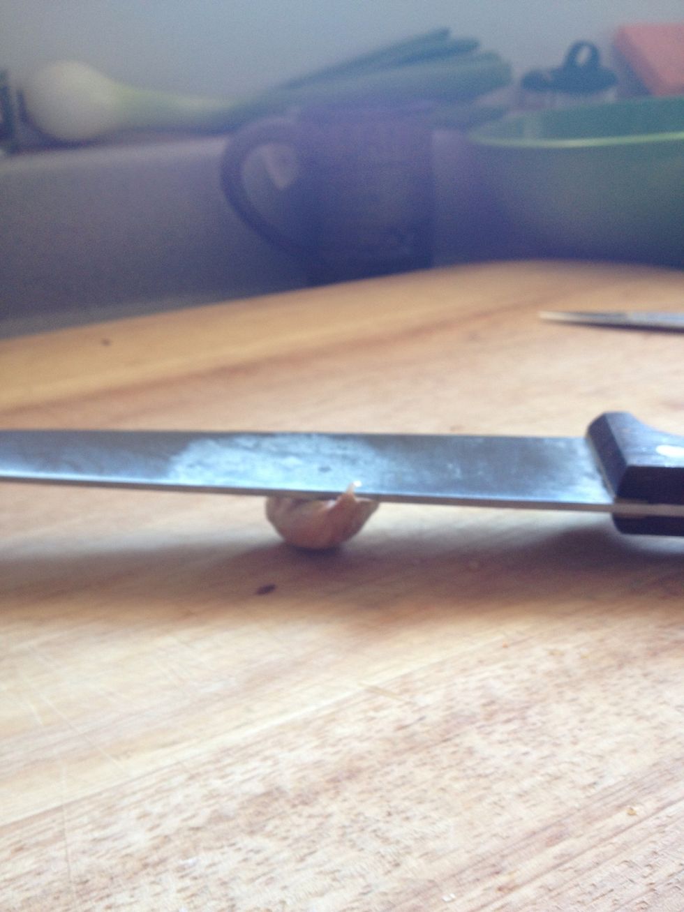 Smash a piece of garlic with a wide knife to get the skin of easily. Watch your fingers!