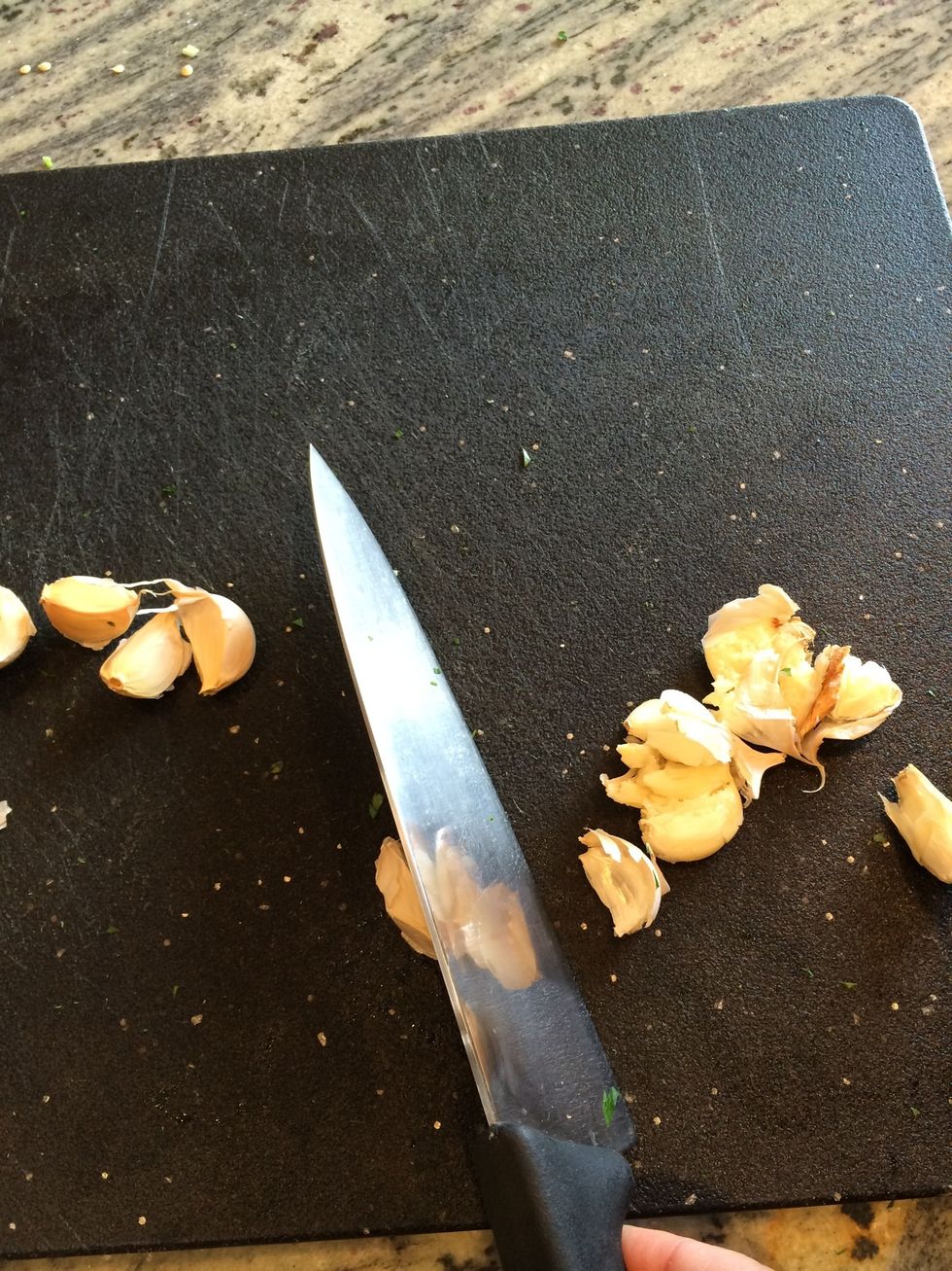 Smash each clove on the cutting board using the knife and the palm of your hand as in next 2 photos