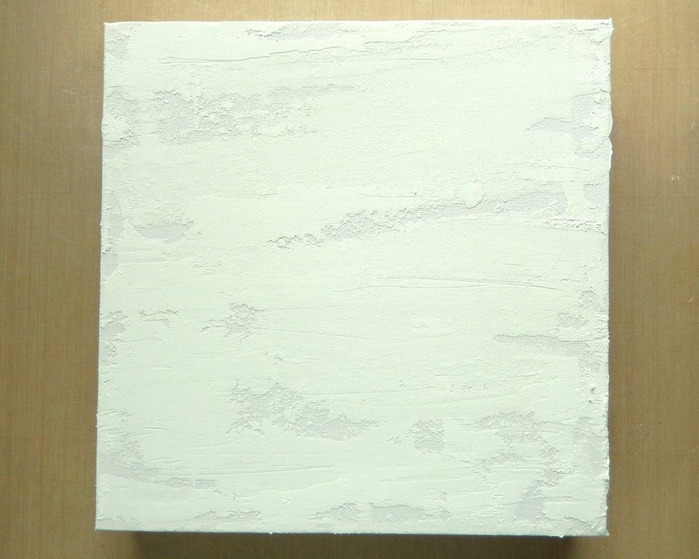 Smear Texture Paste over your background in an uneven fashion leaving some parts of the canvas uncovered and scratch marks evident. Leave to air dry completely.