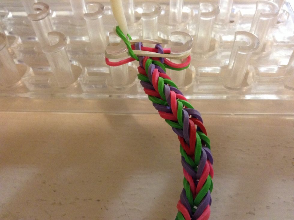 So,before you finish add two more rubber-bands that are two different colors. And, then take the bottom rubber-band and bring it up and over.