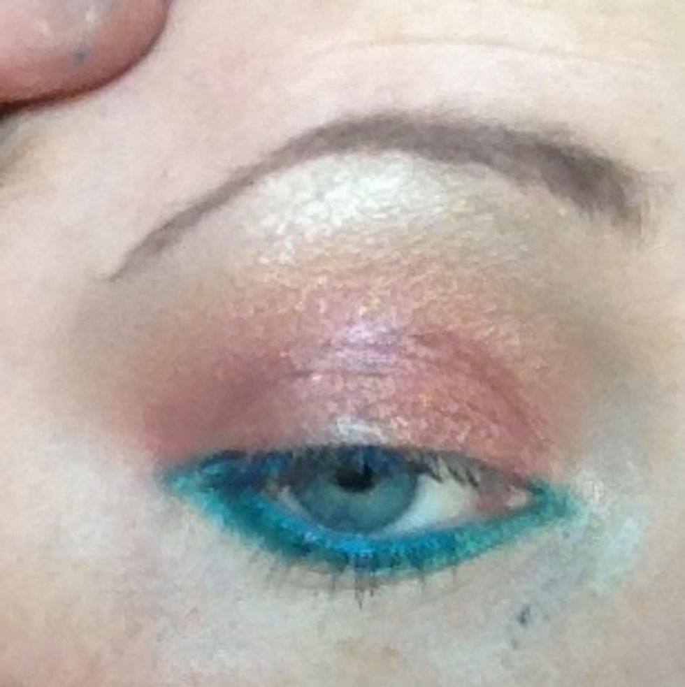 So now below the lower lashes I've added on a small brush teal Mac pigment ive taken right across to the tear duct. Don't worry this is messy and will go all over your face but we wipe this away