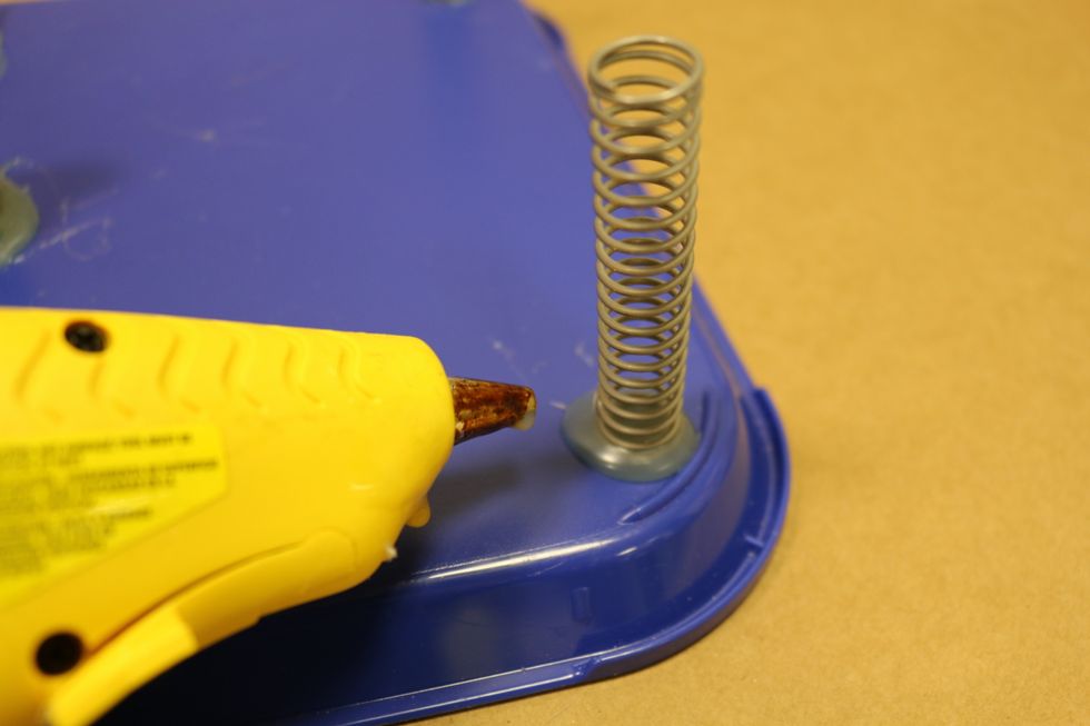 So to get started, we are going to attach 4 spring to each corner of the tray using the hot glue.