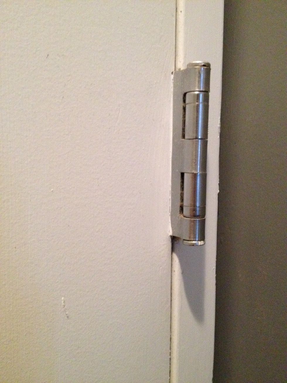 Some hinges have a lock at the bottom. Use the flathead and hammer to tap out the bottom pin lock and then remove the pin as shown in the next step. You can select to do this on any hinge.