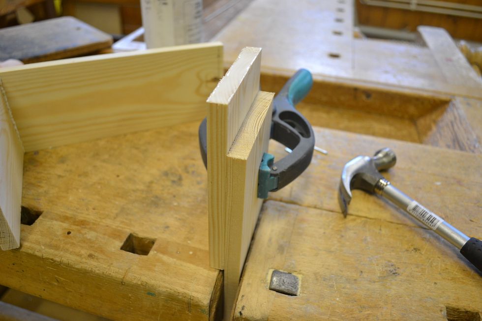 Sp\u00e4nn fast en ledig br\u00e4da i b\u00e4nken s\u00e5 att den sticker upp ca 10 cm. St\u00e4ll den andra kortsidan j\u00e4mte och s\u00e4tt ihop den med en limkl\u00e4mma eller skruvting.