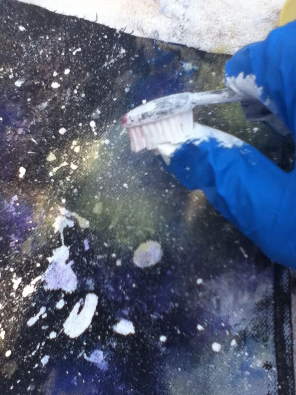 Splatter some more white paint over the entire jean using the toothbrush.