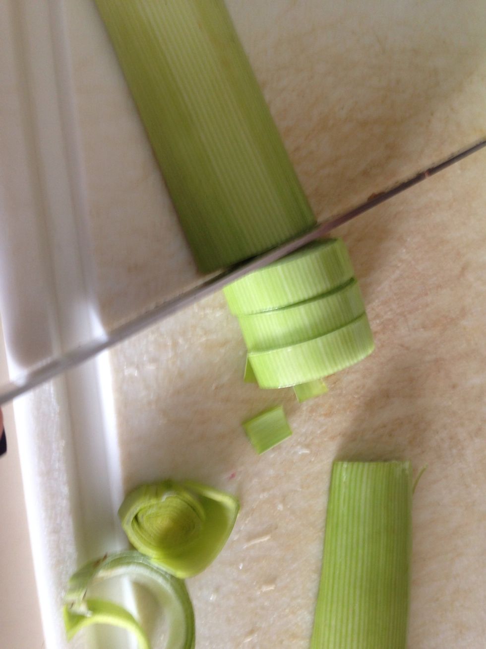 Split the leeks lengthwise and slice them into half moons. Put the sliced bits into a bowl of water and mix thoroughly to get the sand out. Then drain w a colander.