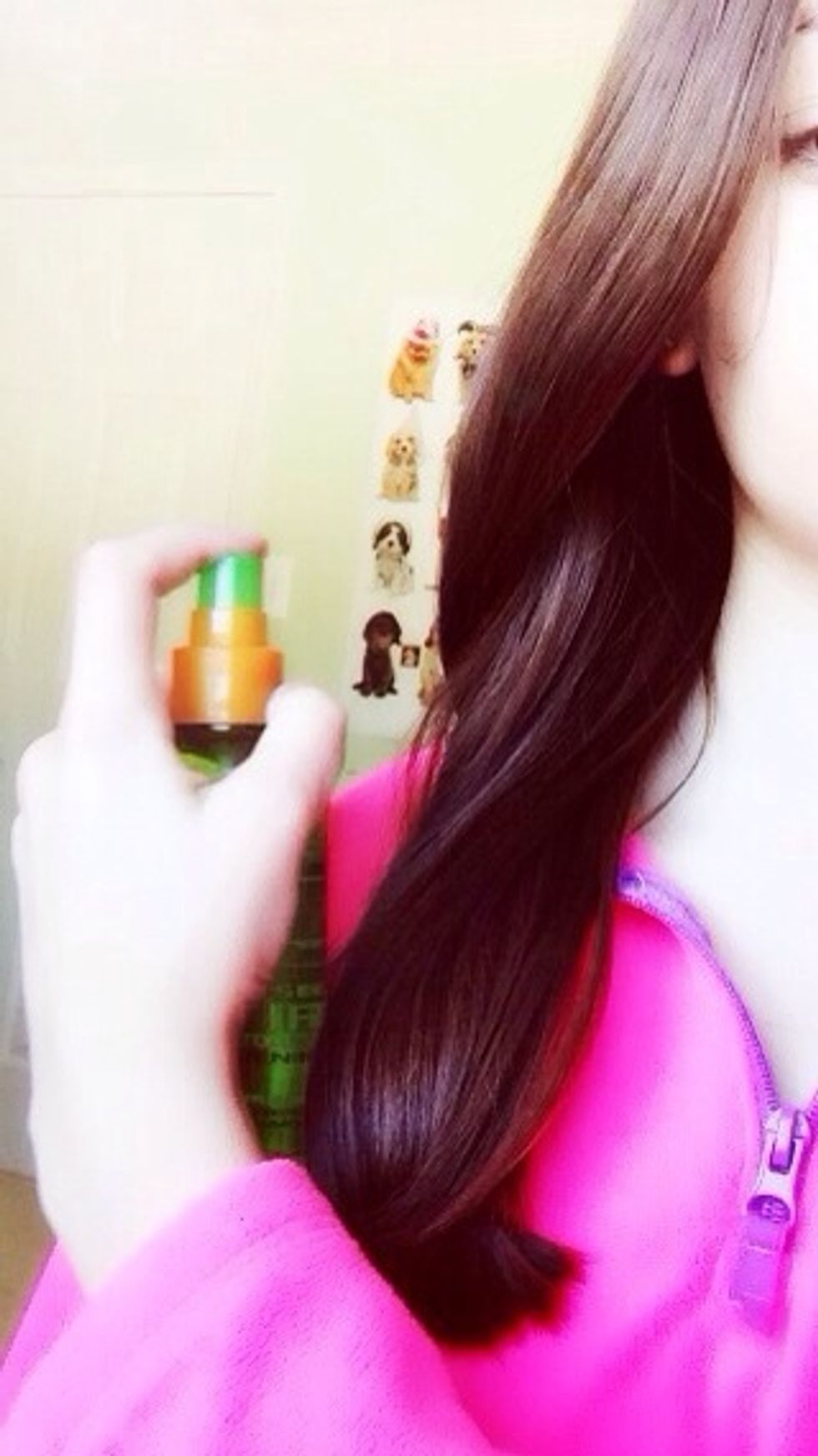 Split your hair into 2 sections and pull one section over your shoulder then spray with heat protectant