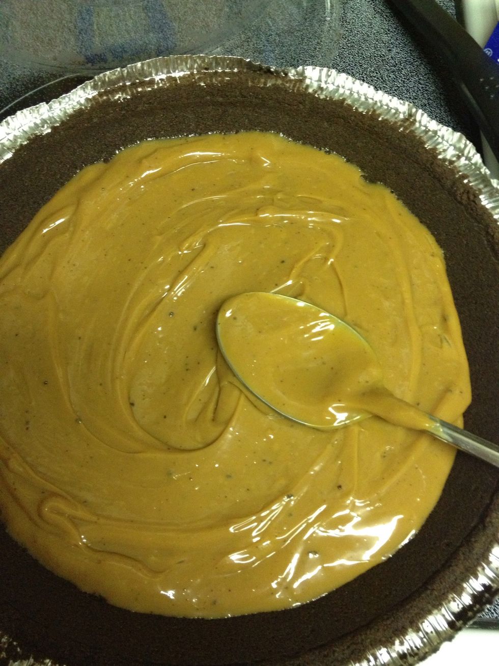 Spoon caramel from bowl into pie crust.