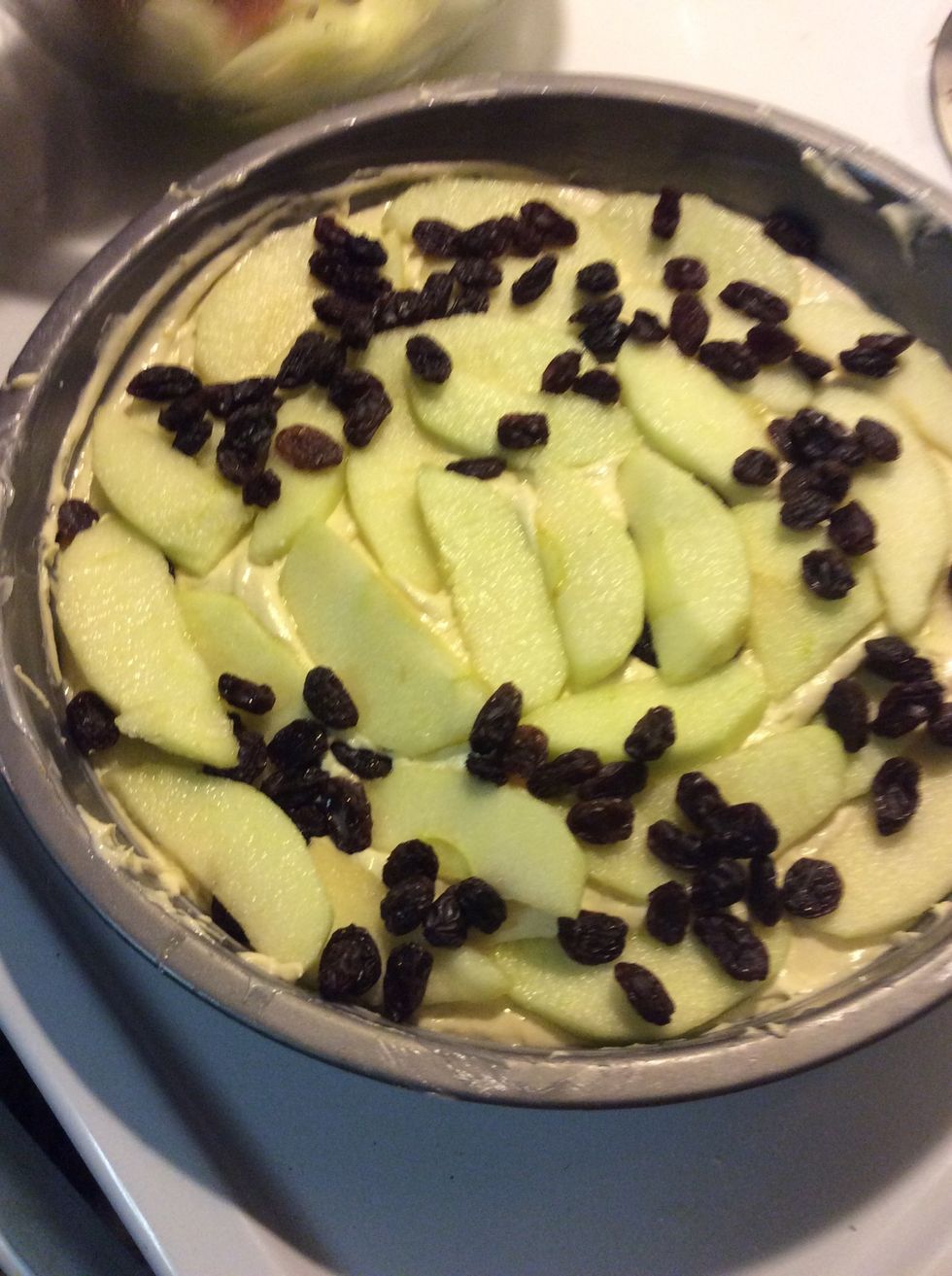 Spoon half the mixture into the prepared cake tin and arrange apple slices on top.