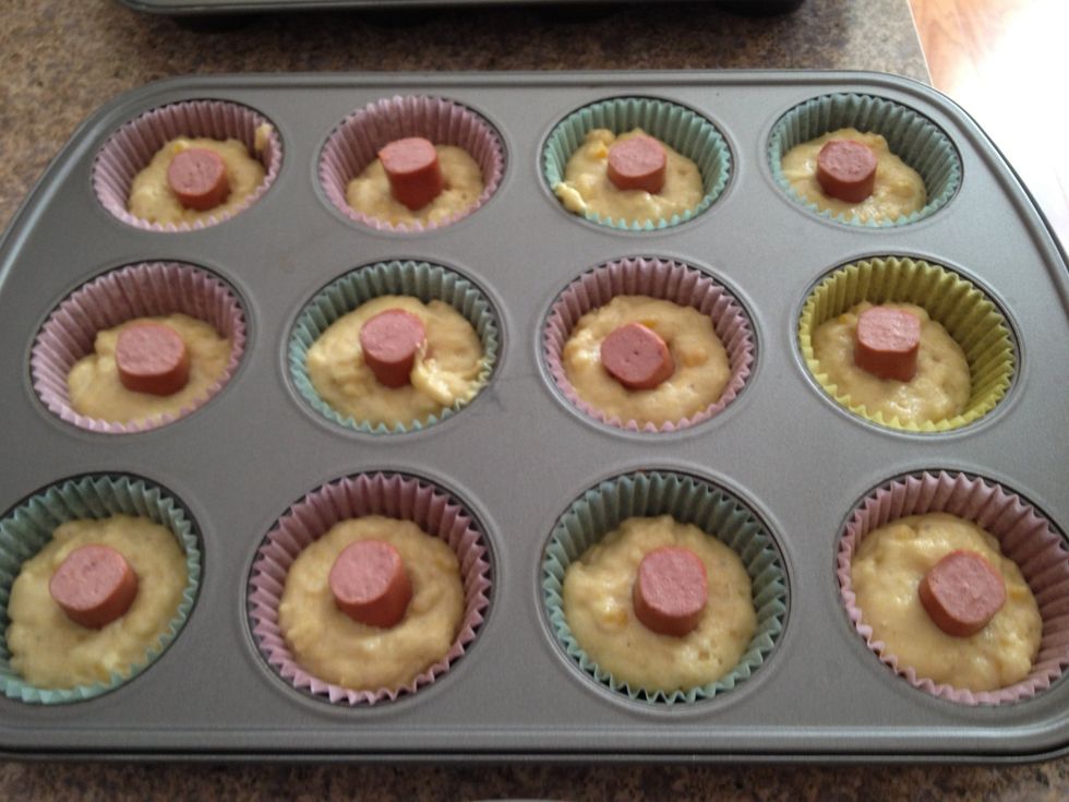 Spoon the batter into the muffin cups, filling the cups 3/4 full. Place a hot dog piece in the center of each muffin cup.