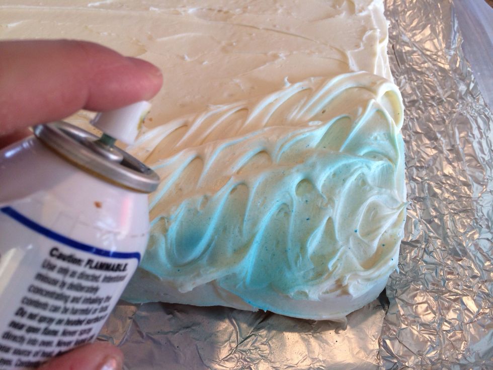 Spray blue food coloring on the waves. If you can't find the spray, coloring the frosting before spreading works too!