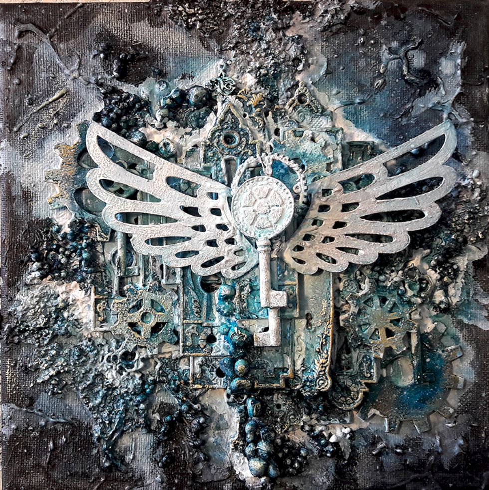 Spray on canvas until it's covered. Paint two keys and chipboard wings with white gesso. Adhere keys and wings to center of metal embellishments pile.