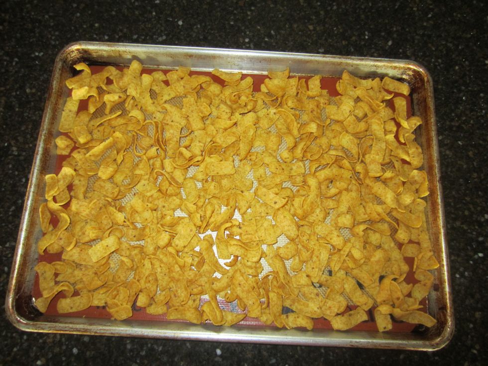 Spray the cookie sheet with cooking spray or put a silicone baking sheet on it, then, spread the Fritos evenly across the cookie sheet.