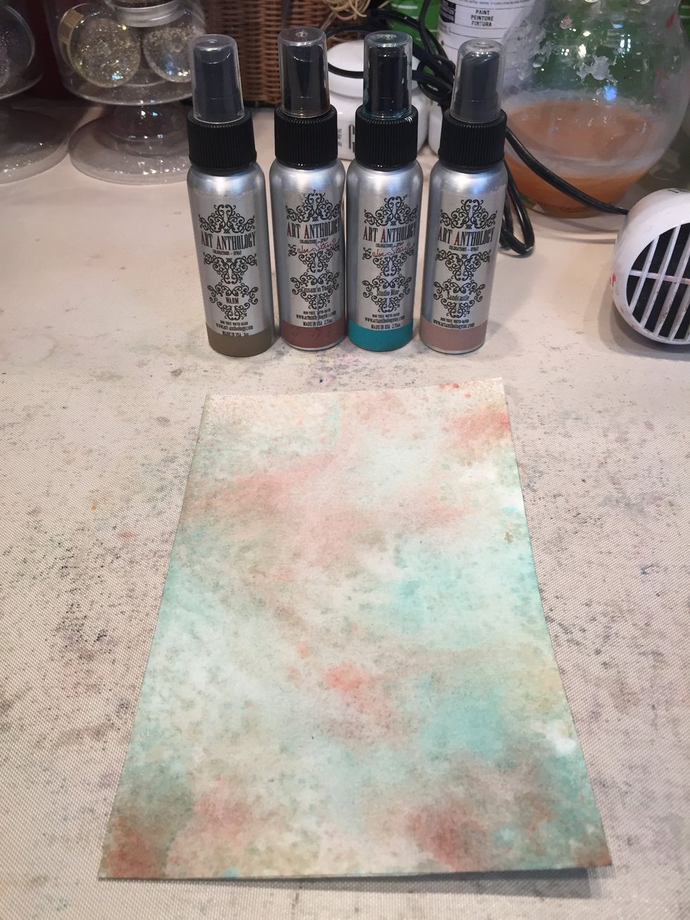 Spray your watercolor paper with your Colorations. Let dry for about a minute, then lay a piece of paper towel flat on the paper and rub one way to remove excess spray.
