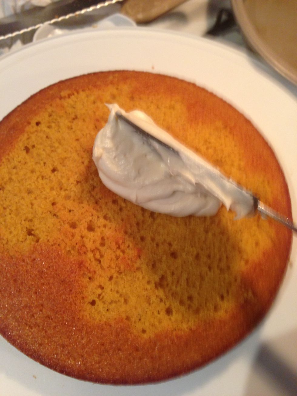 Spread a generous amount if frosting to begin your layered cake.