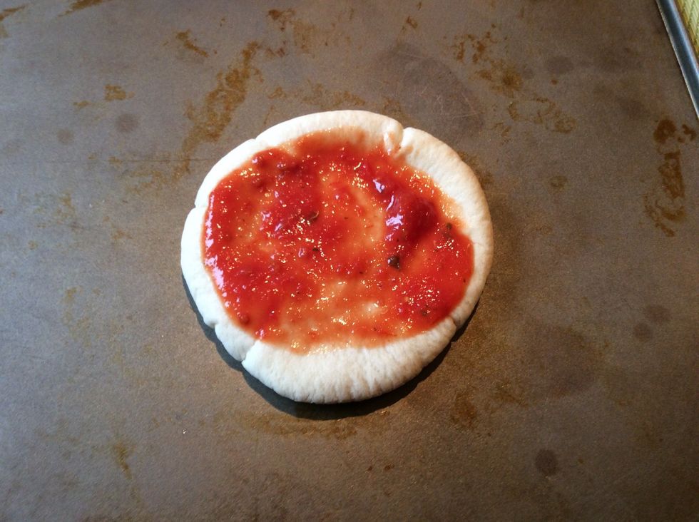Spread a minimal amount of pizza sauce onto the pitta bread
