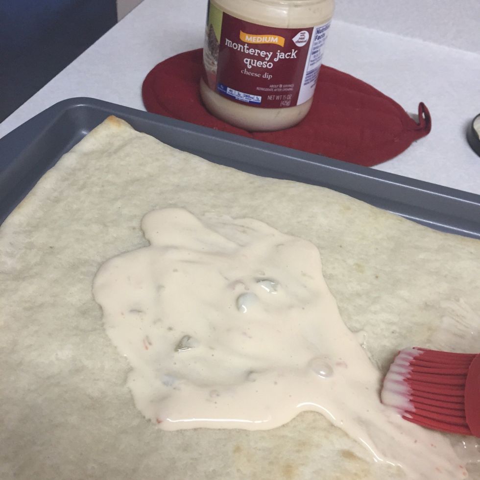 Spread con queso mix thickly on pizza crust