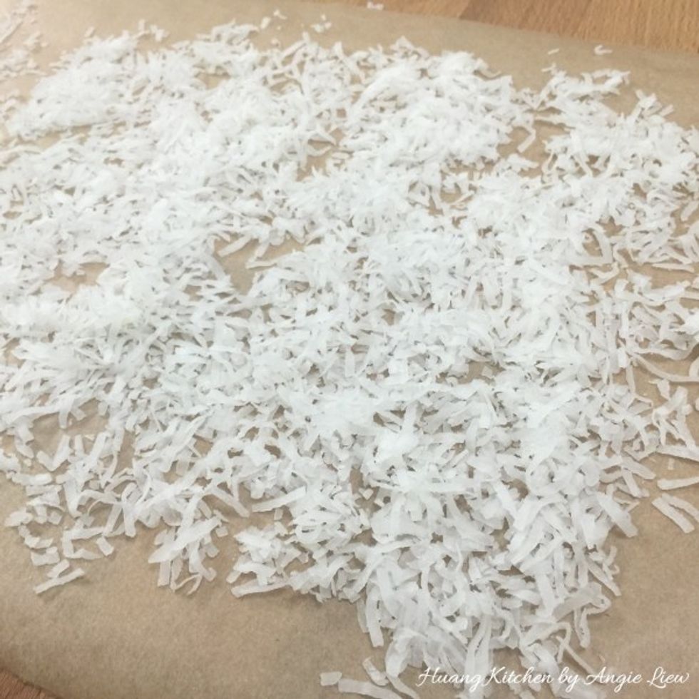 Spread flaked coconut evenly on a sheet of waxed paper.