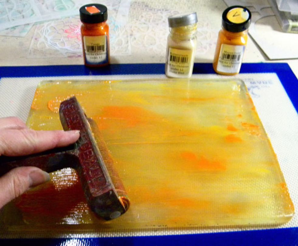 Spread out the paint on the Plate using a brayer.  The three colors that I used are Tango, Buttercream and Mayan Gold.  I keep scrap paper nearby to clean the paint off of the brayer.