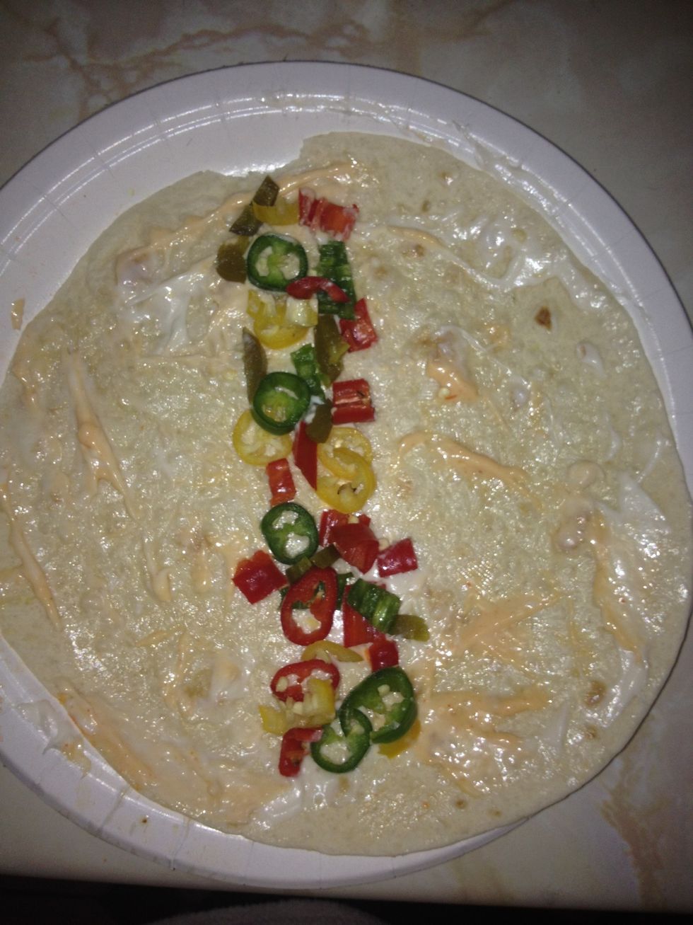 Spread out your peppers and jalape\u00f1os, once you have spread your sauce on the wrap, I use taco dip and mayonnaise because the taco dip is spicy, but u can use another spicy sauce that you like.