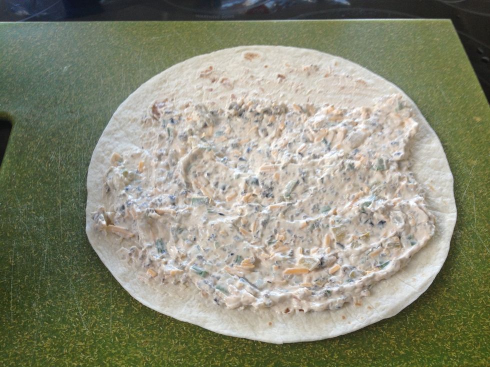 Spread over 80% of tortilla, leaving far end uncovered.  When you roll it up you'll need some free space at the end for the excess mixture to roll on to.