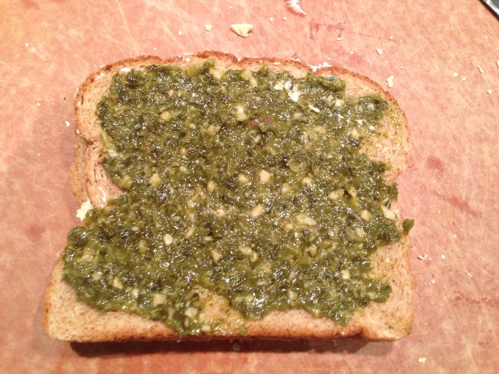 Spread pesto on one side of the bread (opposite side of the butter, this will be the inside of the sandwich)