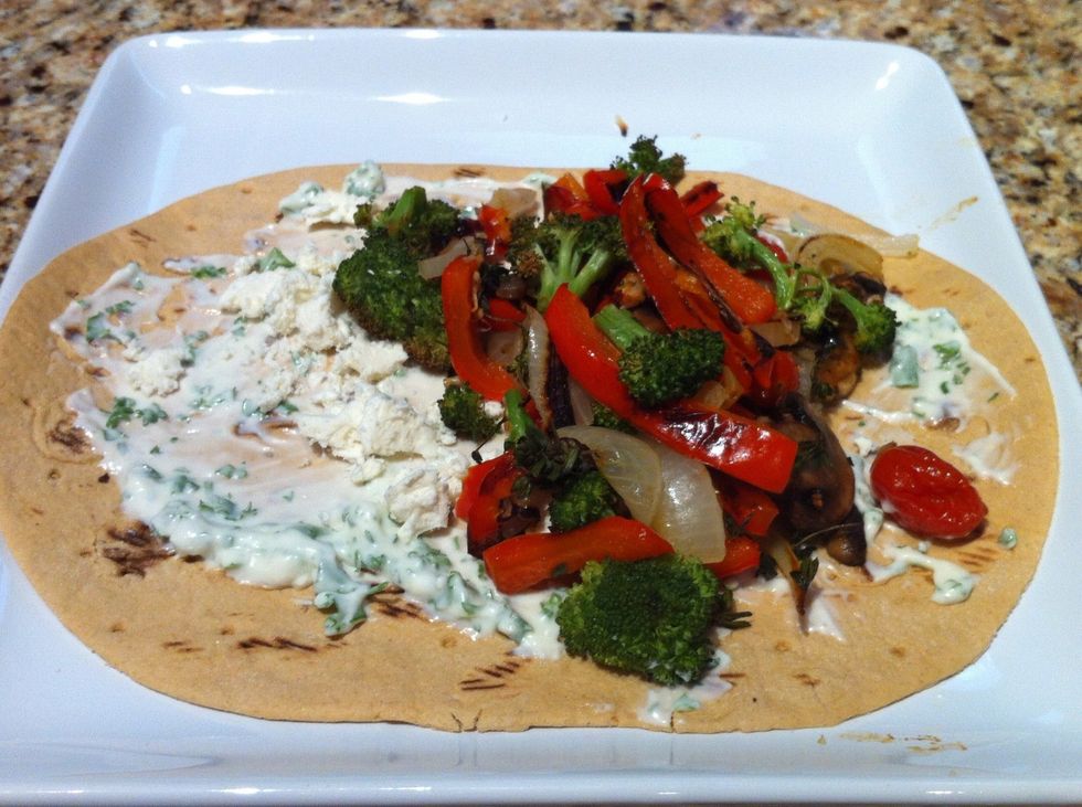 Spread sauce, feta cheese and vegetables over flatbread and roll up. Slice in half.
