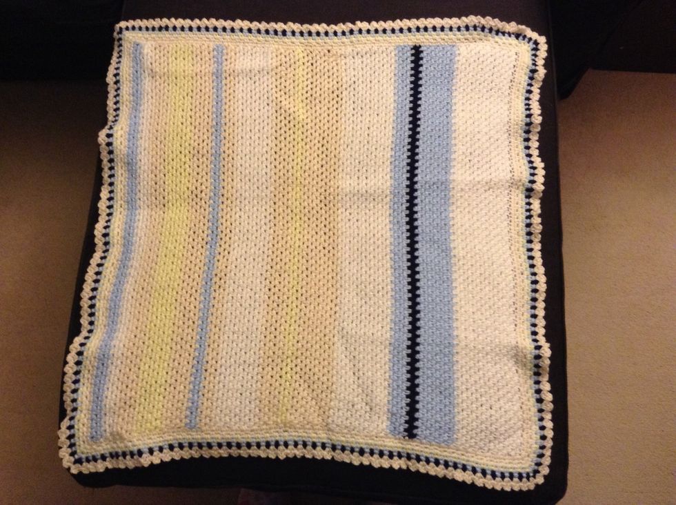 Spread the afghan on a flat surface you can pin it to. A bed or a sofa will work.