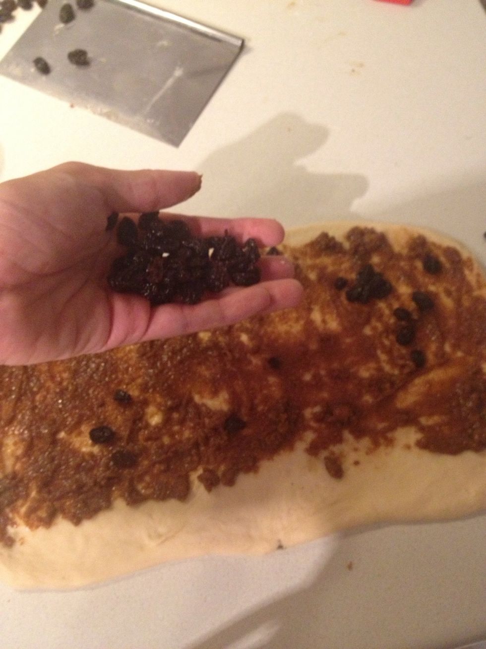 Spread the butter - sugar over the dough. Drop some raisins in. Leave an inch of clear dough at the bottom.