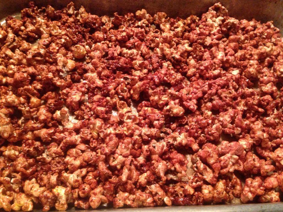 Spread the coated popcorn flat on the cookie sheet.