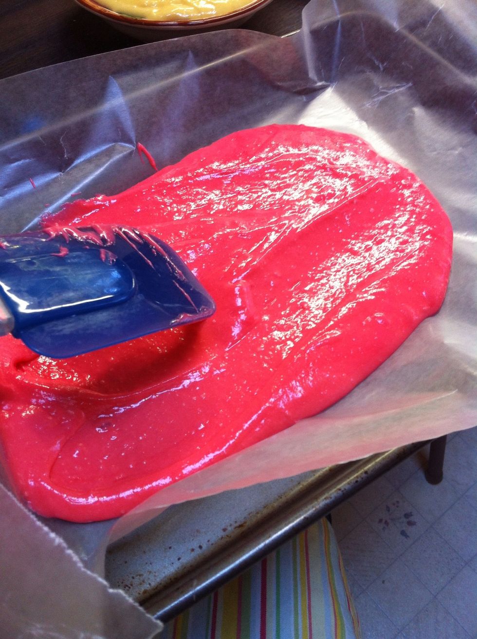 Spread the first color evenly on to the pan. Line the pan with parchment paper and have it hang over the edges for easy removal.